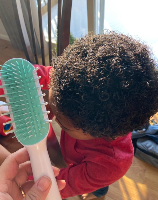 The curls of the reviewer’s child after using the brush they’re holding