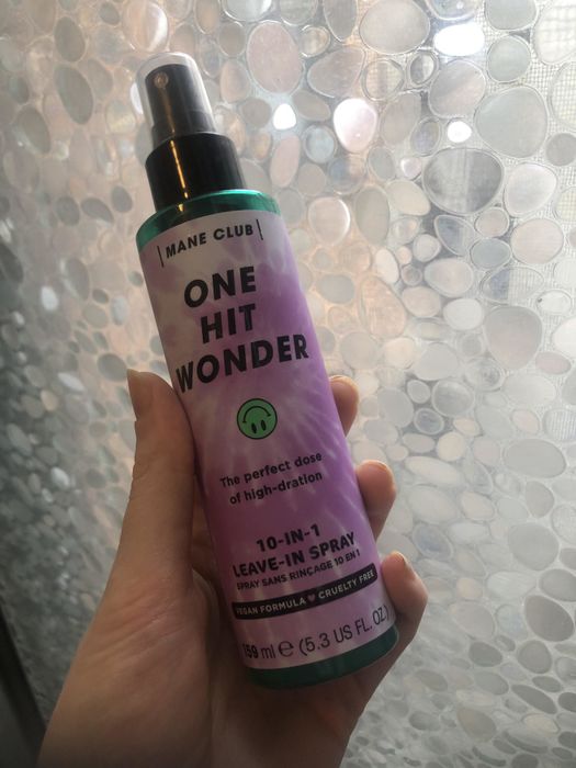 A hand gripping the bottle of the product