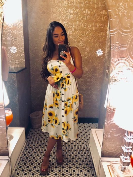 A reviewer wearing the same dress in white with a sunflower pattern