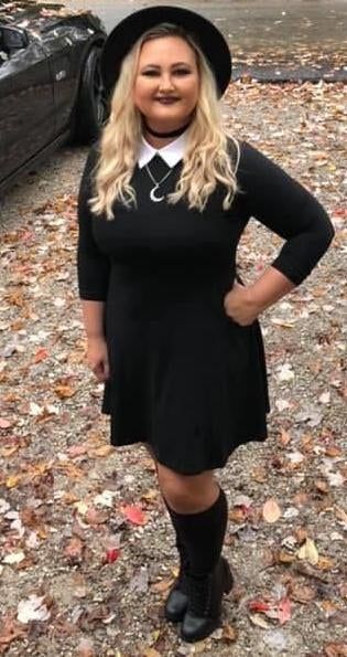 reviewer pairing the black dress with black boots and a black hat
