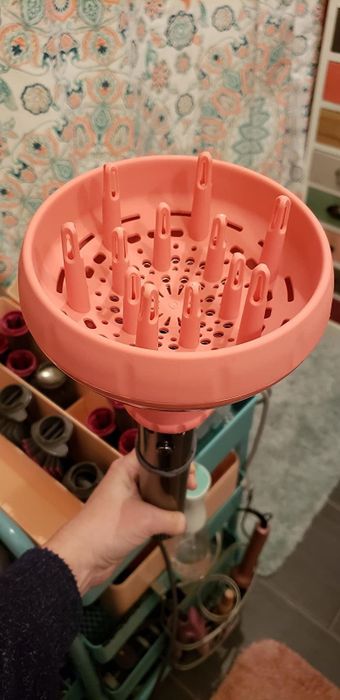 A reviewer showing a dryer with the pink diffuser attachment in use