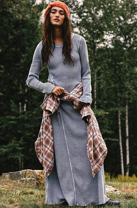 The model is sporting a blue dress, with a flannel shirt tied around their waist.