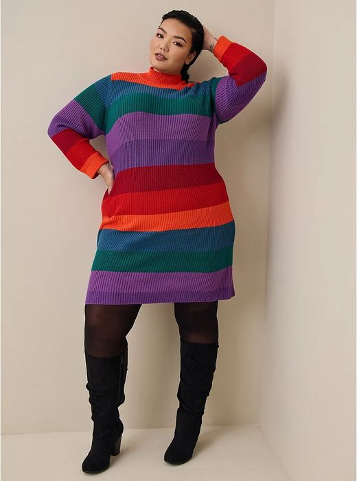 The model is showcasing a multicolored striped dress paired with black tights and boots.