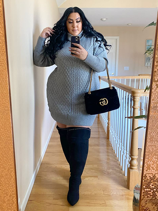 The reviewer is wearing a gray dress paired with black boots.