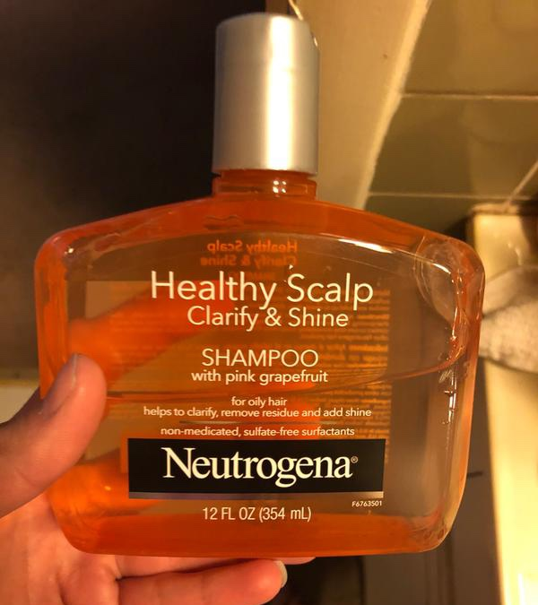 A reviewer holding the bottle of shampoo