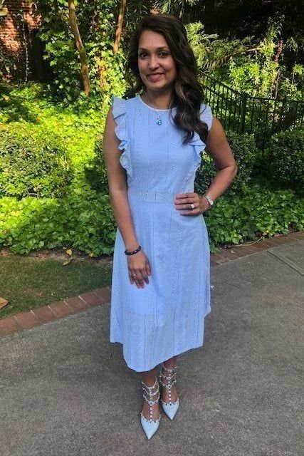 A reviewer wearing a blue below-the-knee dress