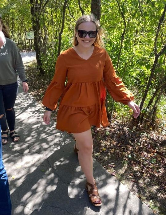 A reviewer wearing the dress in orange