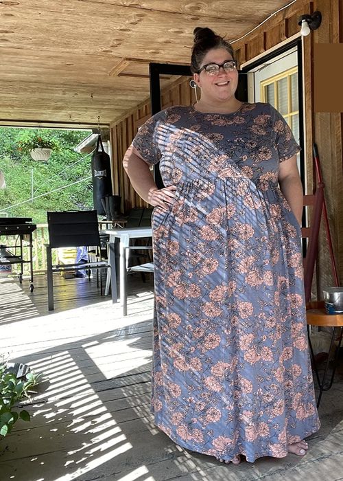 A reviewer wearing the dress in blue adorned with a tan floral print