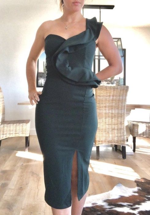 A reviewer wearing a green one-shoulder ruffle dress
