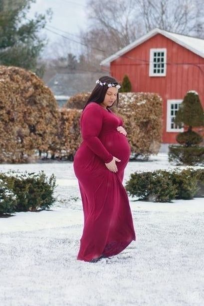 A reviewer expecting a baby showcases a red maxi dress.
