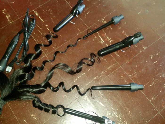 The various barrel attachments placed next to locks of hair, demonstrating the different curl types they create, from loose waves to tightly coiled curls