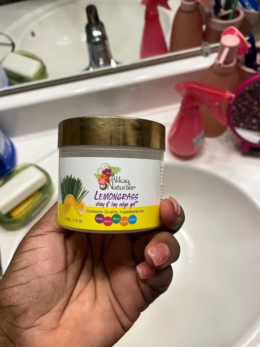 A reviewer's hand showcasing the container of edge styling gel.