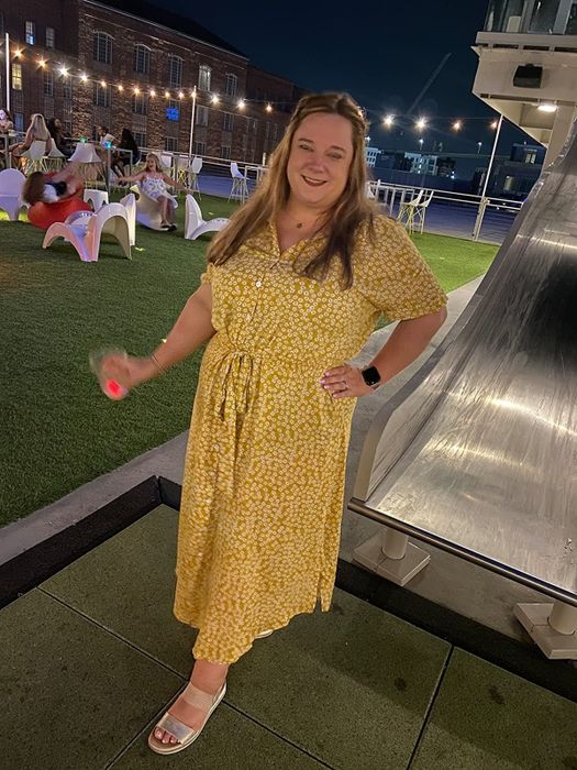 A reviewer wearing a short-sleeve tie-front midi dress in a yellow and white floral print