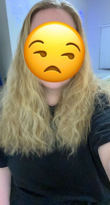A reviewer showing their frizzy curly hair before use.