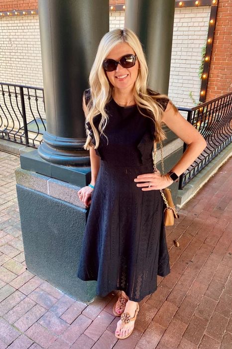 A reviewer wearing a black below-the-knee dress