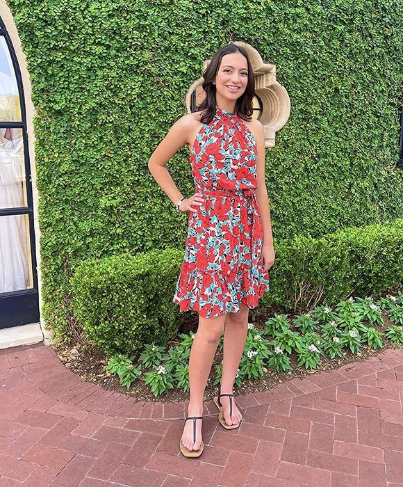A reviewer modeling the same dress in a vibrant blue and red floral pattern