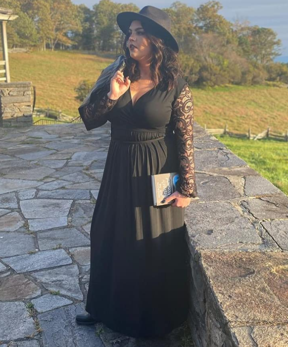 reviewer wearing the black dress and a black hat