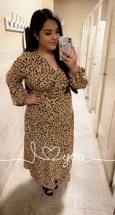 A reviewer wearing the dress in a colorful patterned design