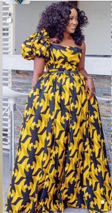 A model in a one-shoulder maxi dress with voluminous fabric.
