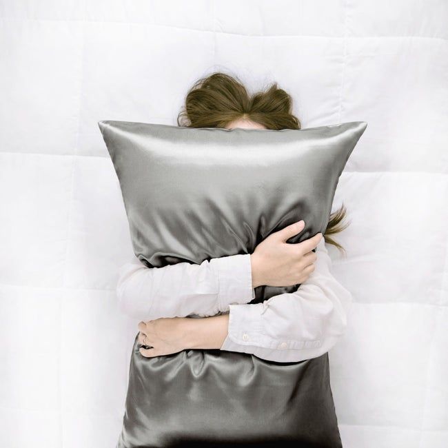 A model holding a sleek grey satin pillow
