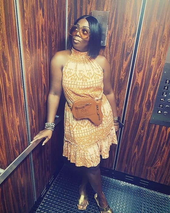 A reviewer wearing the dress with a patterned design, paired with gold sandals