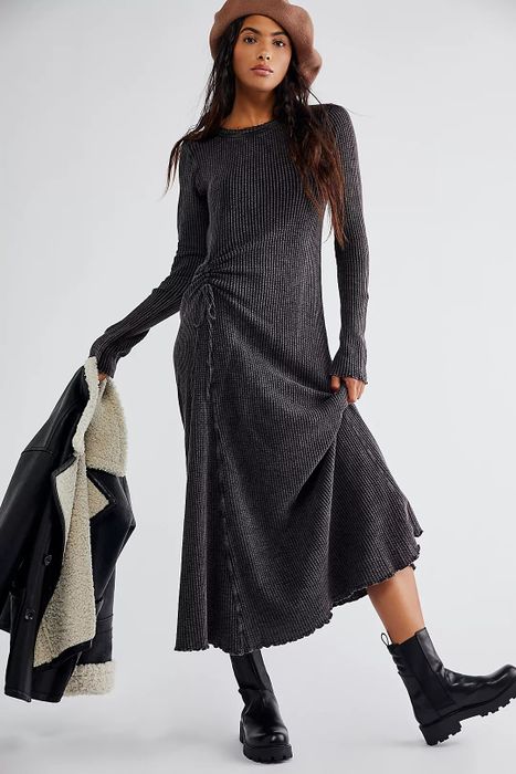The model is dressed in a black dress, complemented by black boots.