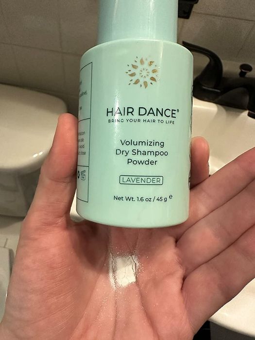 The reviewer holding the dry shampoo, showing some powder in their palm