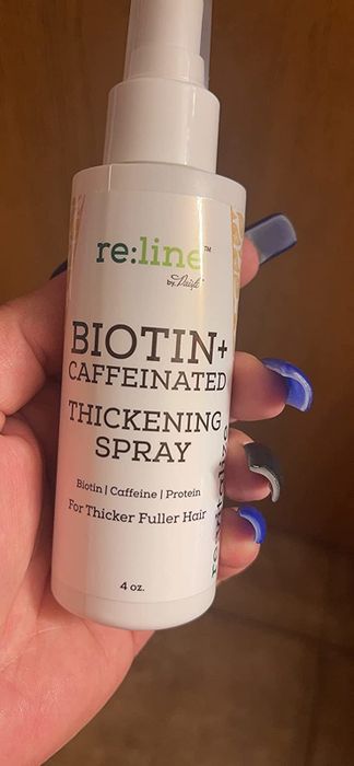 Reviewer holding the hair thickening spray