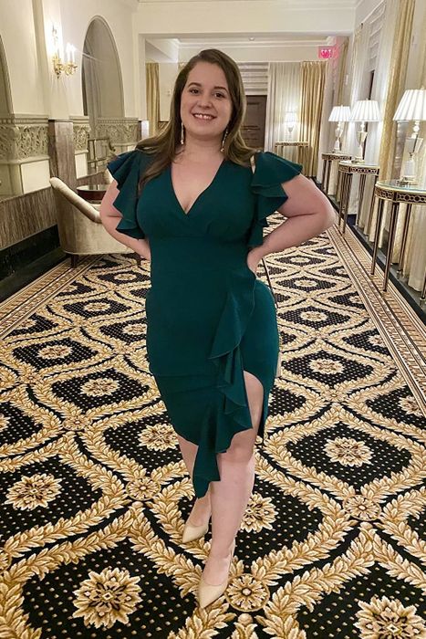 A reviewer wearing a green slit ruffle dress