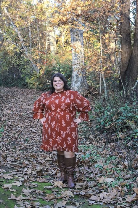 A reviewer in an orange dress paired with brown boots