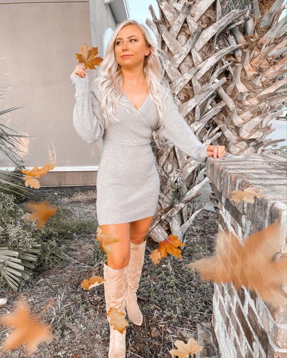 The reviewer is dressed in a gray dress, complemented by knee-high boots.