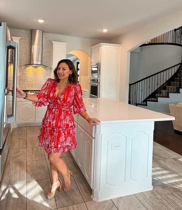 Reviewer wearing the red version of the dress with brown sandals