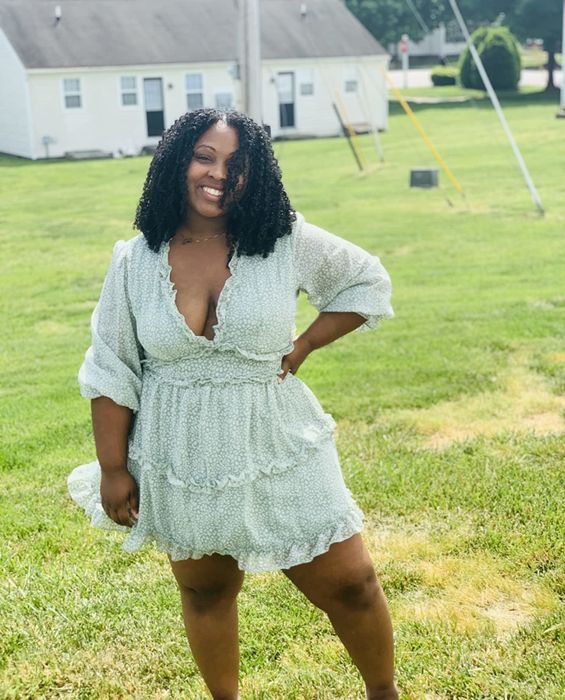 A reviewer wearing a long-sleeve green ruffle dress