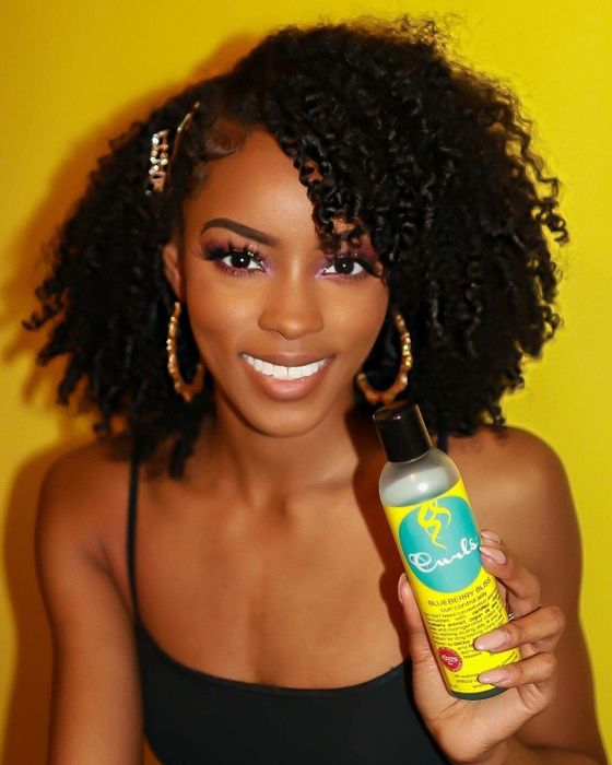 Model holding the product and showcasing her bouncy ringlet curls.