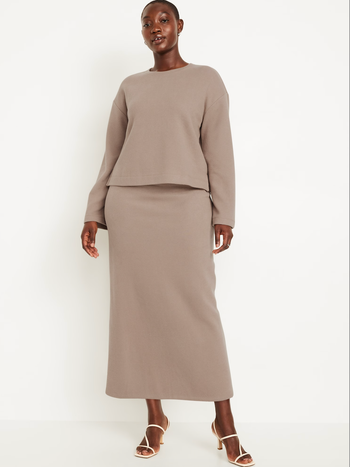 Person dressed in an elegant long sleeve top and matching floor-length skirt, paired with open-toed, heeled sandals