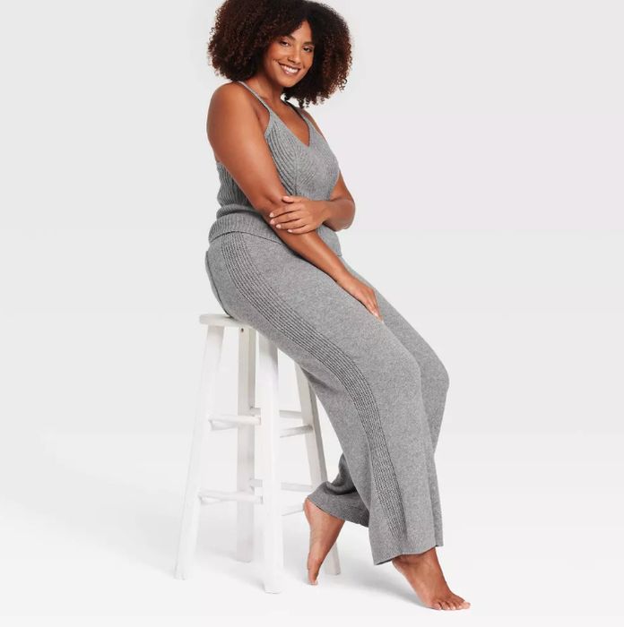 Person sitting on a white stool, dressed in a comfy sleeveless knit top and wide-leg pants, perfect for casual or lounge wear