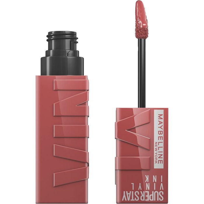 A bottle of Maybelline SuperStay Vinyl Ink liquid lipstick beside its applicator, with the brand name and product line clearly visible on the packaging.