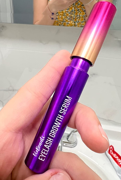 a reviewer holding a tube of the lash serum