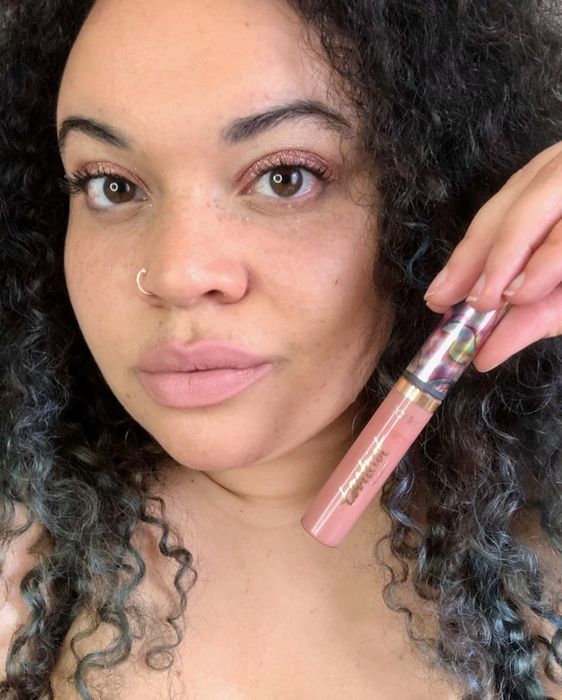 Mytour Shopping reviewer holding the light pink lip paint with a matching lip shade.