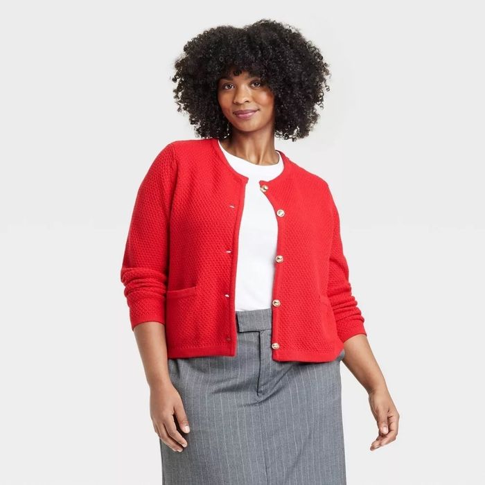 Individual modeling a textured cardigan over a white top paired with a gray skirt, posing for a fashion-focused shopping feature.