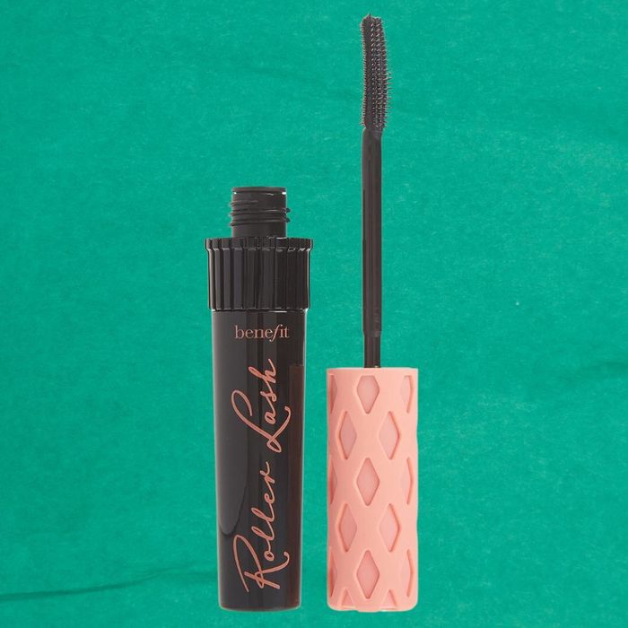 A black tube marked 'Benefit Roller Lash' with an open mascara wand designed for curling lashes. The wand features a curved brush and a textured handle.