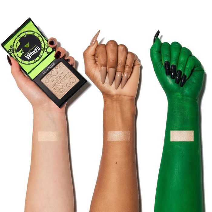 Three hands with different skin tones displaying makeup swatches. The left hand holds a