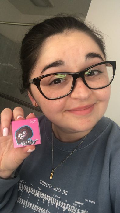 The editor showcasing a subtle lip color while holding up the product.