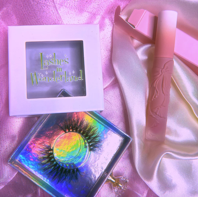 A set of lashes and a tube of lip gloss, both adorned with bows engraved on them.