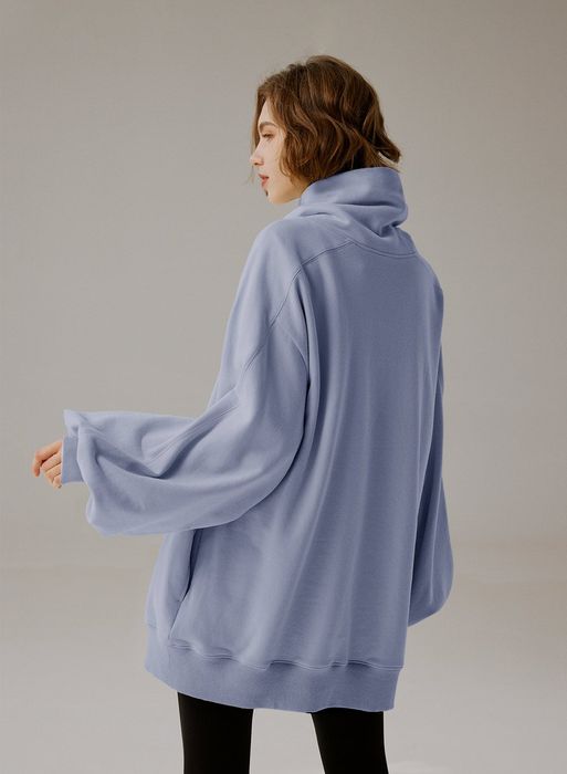 Same model from the back, donning the sweater in a soft light blue shade.