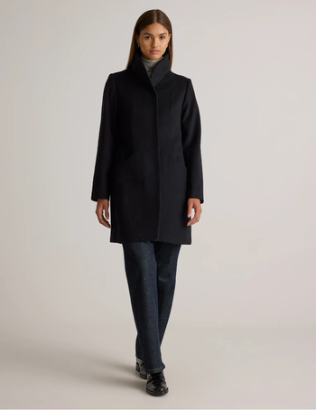 Model showcasing a tailored coat, turtleneck sweater, jeans, and loafers, featured in a winter fashion guide.