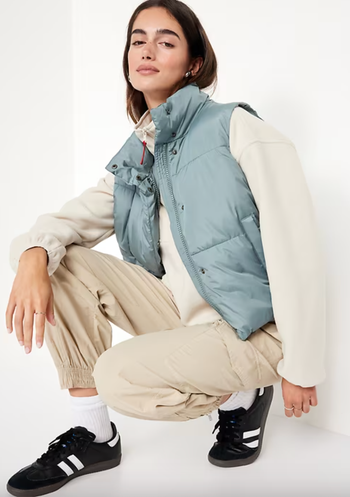 A model sports a puffy vest over a laid-back outfit, including a sweatshirt, joggers, and sneakers