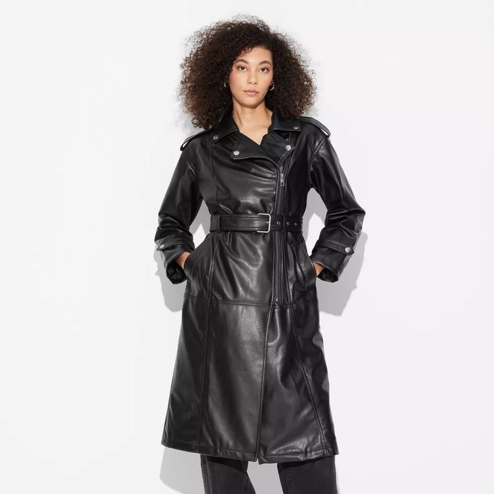 A person sporting a long belted leather coat featuring a stylish collar and distinctive button details.