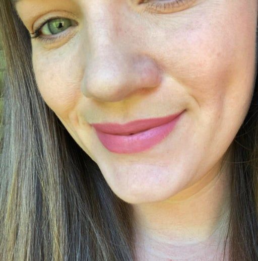 Close-up of a smiling reviewer wearing a pink lip crayon and sporting straight hair.