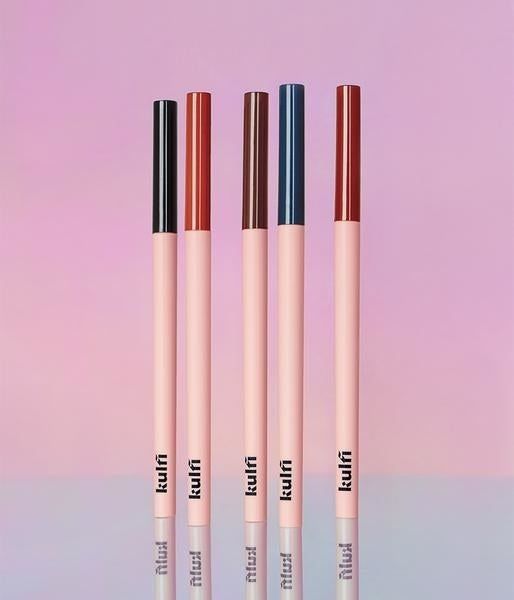 The five eyeliners neatly arranged against a stunning ombre pink background.